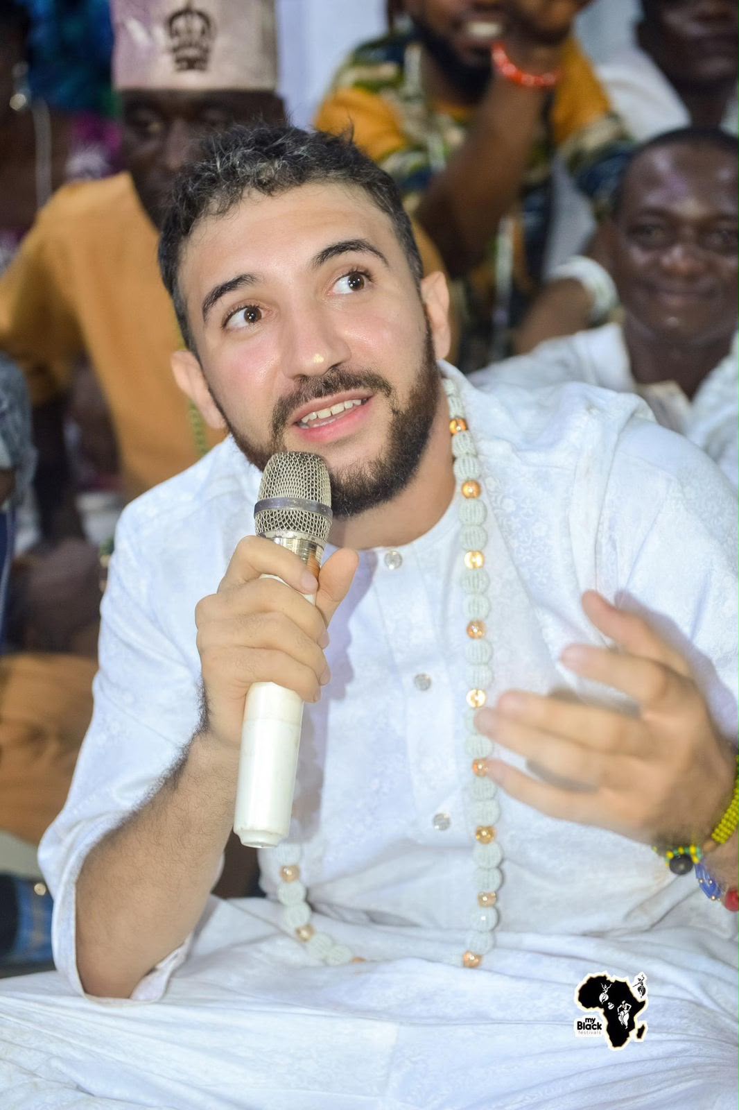 Sahori Gamez vestido de blanco, hablando con un micrófono en una reunión