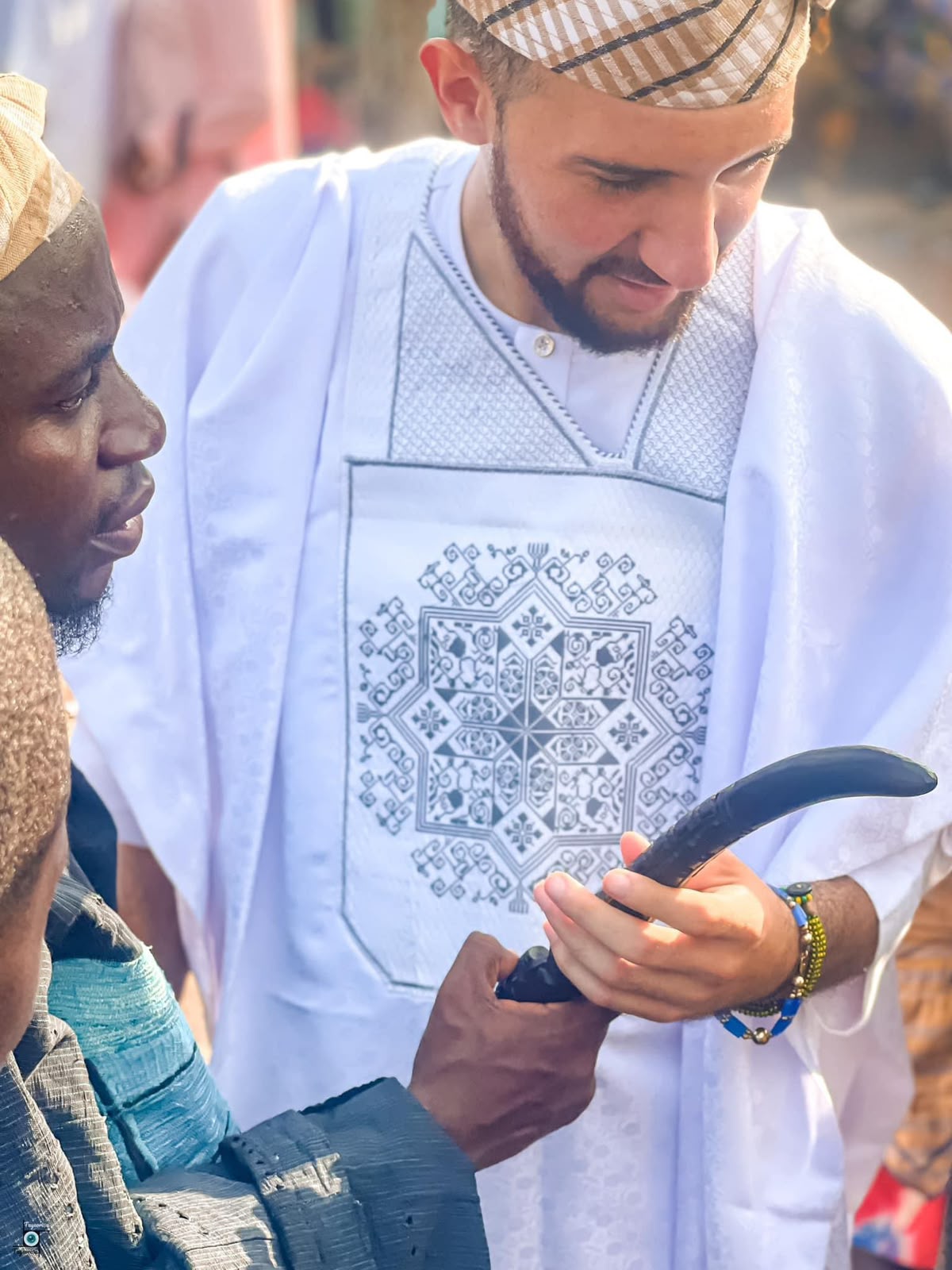 Sahori de blanco recibiendo un objeto ceremonial de un mayor